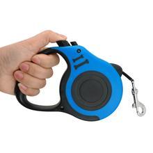 Hand holding a blue pet automatic telescopic traction rope with one-touch control system.