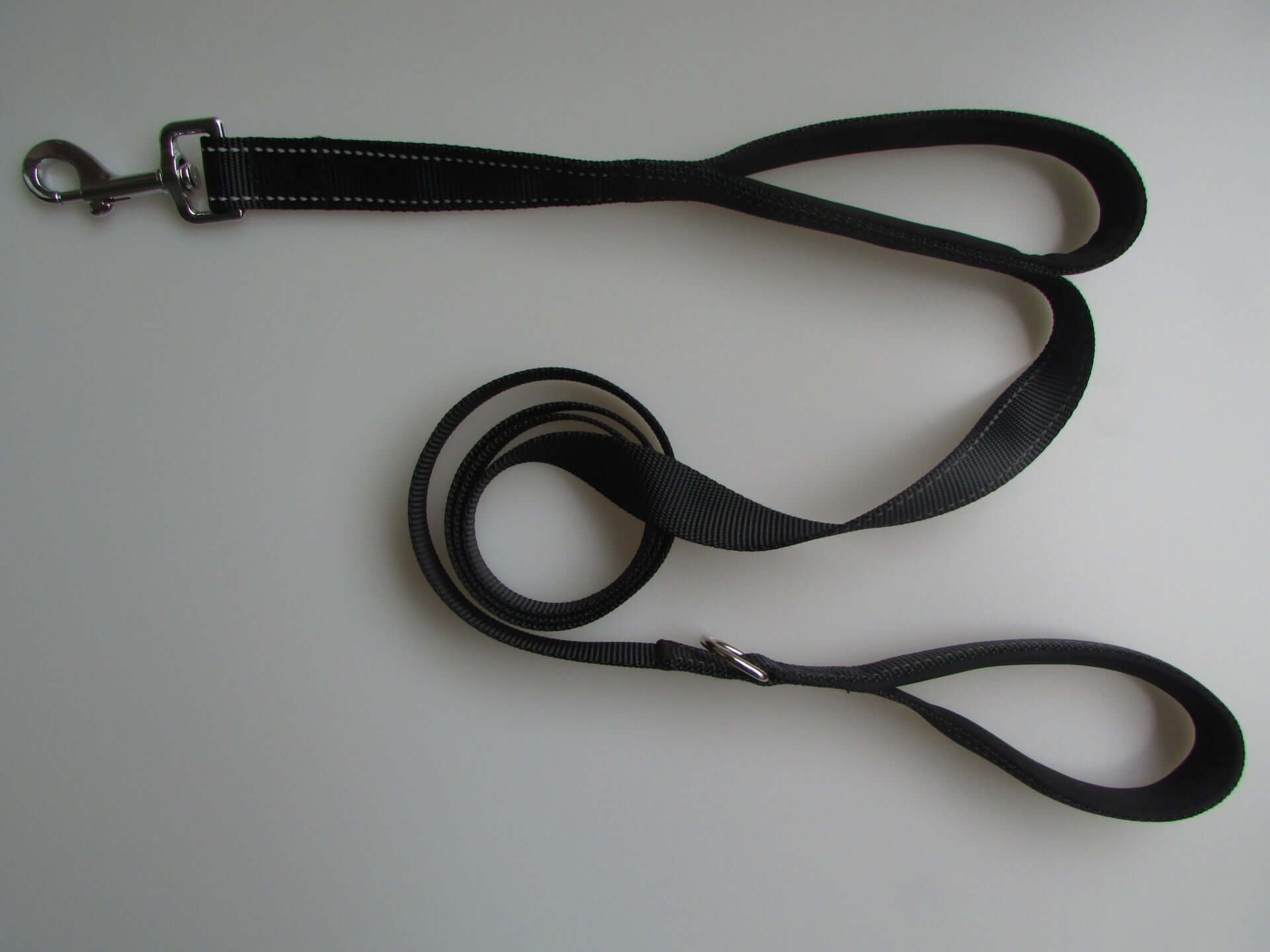 Black double handle pet leash made of durable nylon, featuring a metal buckle and reflective stitching for safety.